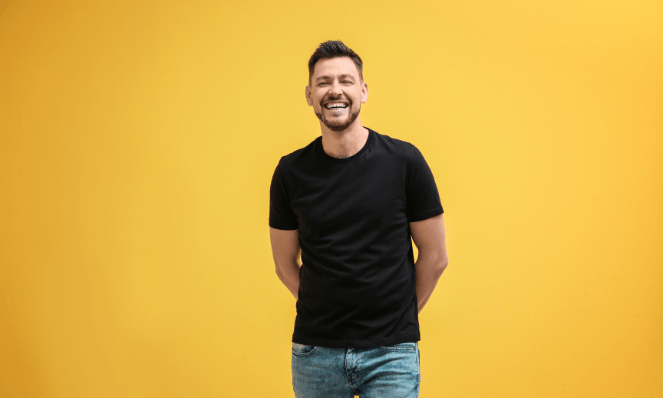 A man in a black t-shirt standing in front of a yellow background.